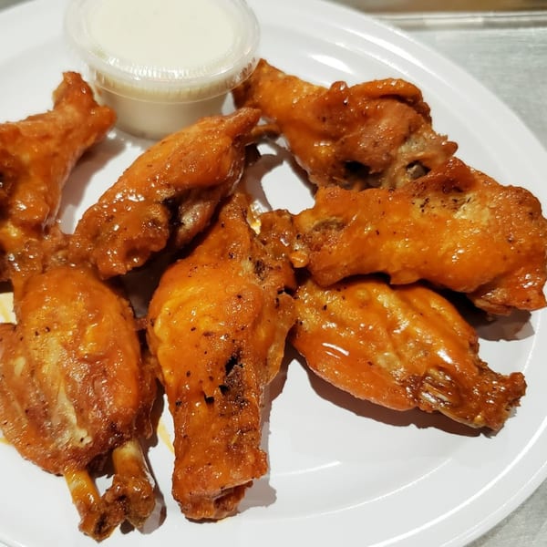 A plate of seven Times Square Kitchen buffalo wings with a side of ranch dressing.