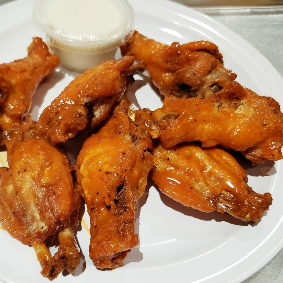 A plate of seven Times Square Kitchen buffalo wings with a side of ranch dressing.