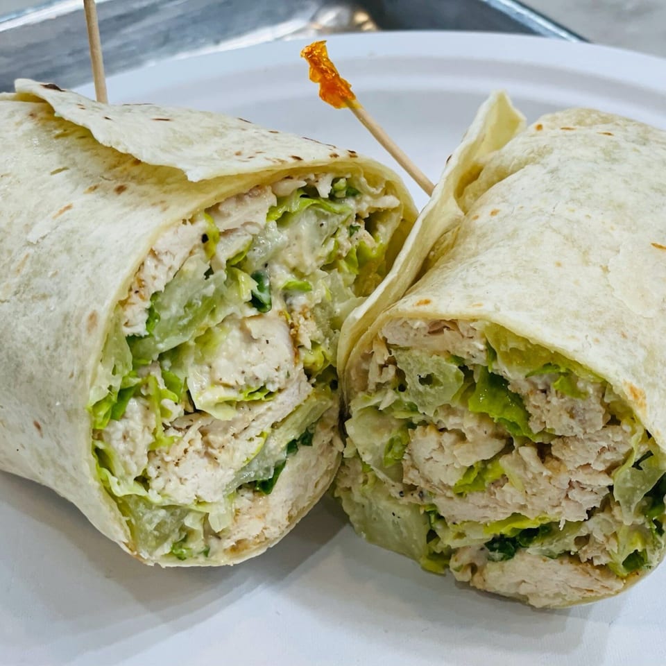 Two halves of a chicken Caesar wrap, filled with chicken, lettuce, and dressing.