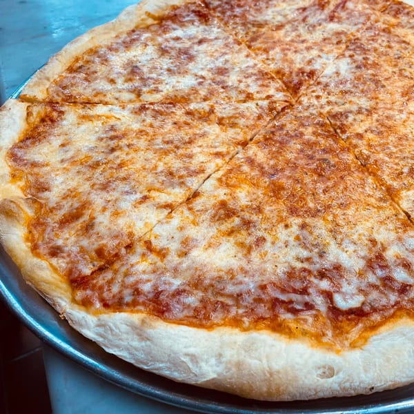 A large, round, cheese pizza from Times Square Kitchen, cut into slices on a metal tray.