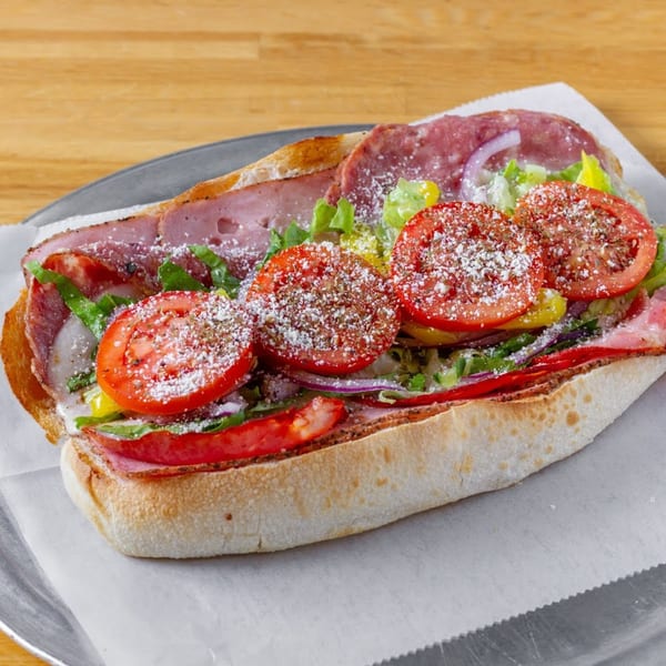 A large, loaded Italian sub sandwich with meats, cheese, lettuce, tomatoes, and onions.